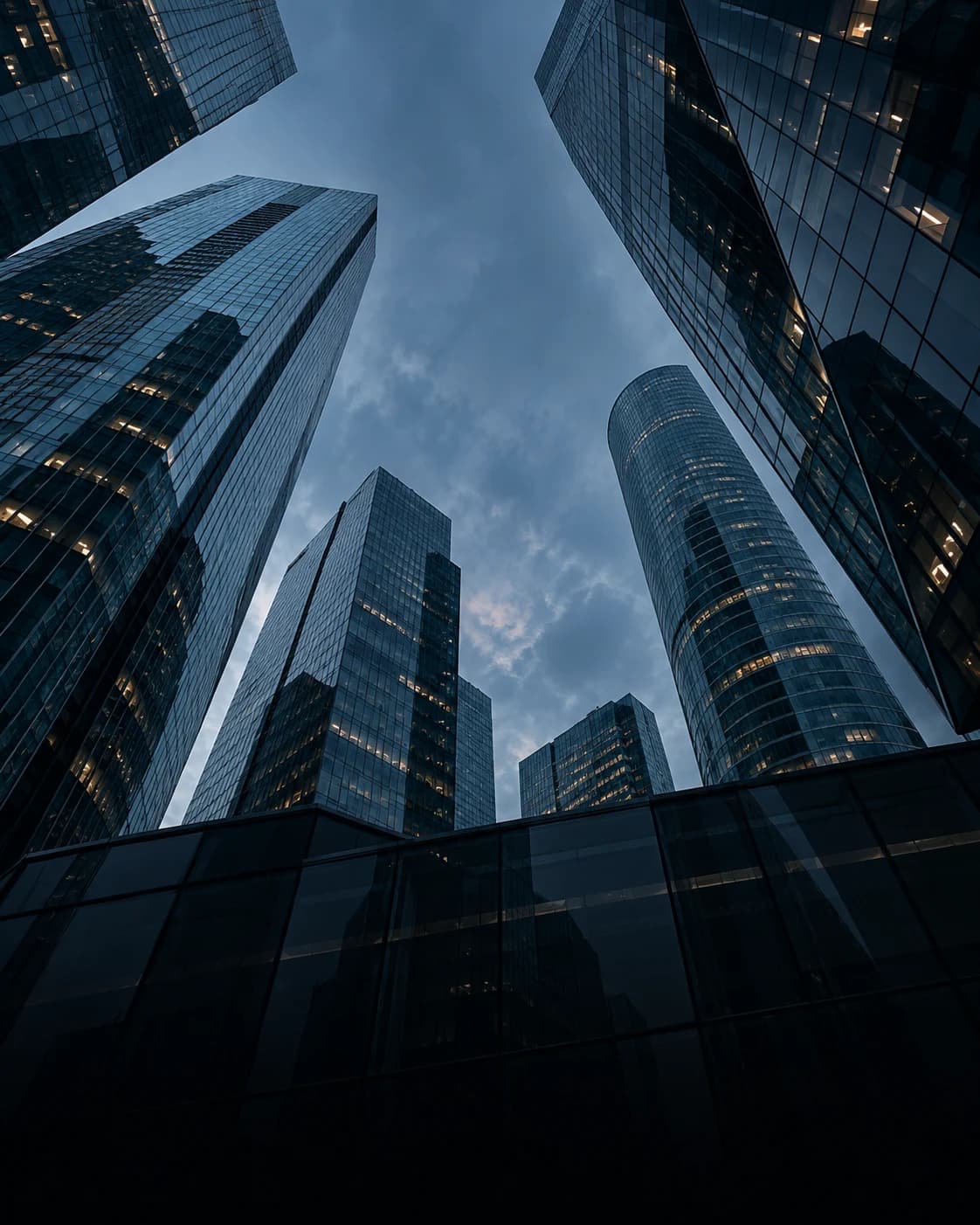 Modern glass office towers viewed from below at dusk